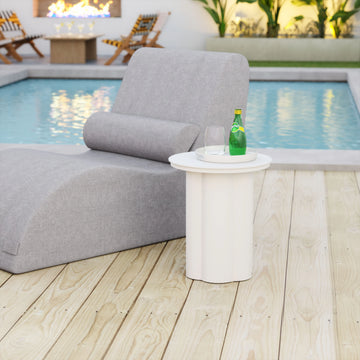Gray outdoor lounge chair with a small table and bottle by a pool