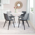 Dining room with a round white table and gray chairs, featuring a decorative mirror on the wall.