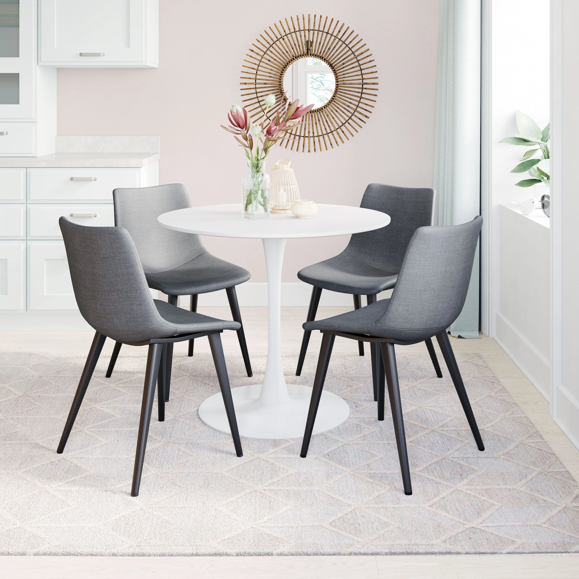 Dining room with a round white table and gray chairs, featuring a decorative mirror on the wall.