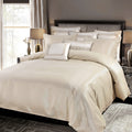 Neatly made bed with beige bedding and decorative pillows in a bedroom setting.
