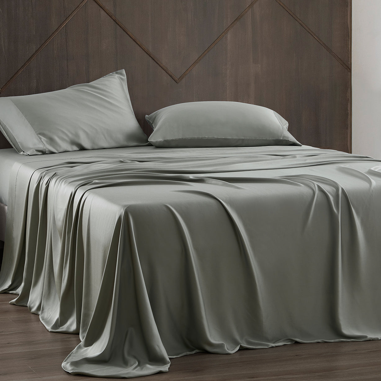 Gray satin sheet set on a bed with a wooden headboard.