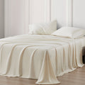 Beige bedspread and pillows on a bed with a neutral wall background