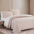 Neatly made bed with pink bedding in a bedroom setting