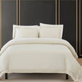 Neatly made bed with white bedding against a dark wall with gold accents