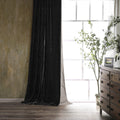 Black curtain in a room with a wooden dresser and plant