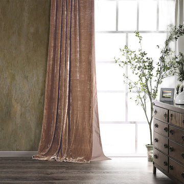 Brown curtain in a room with a window, plant, and wooden dresser.