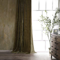 Brown velvet curtain in a room with a wooden dresser and window.