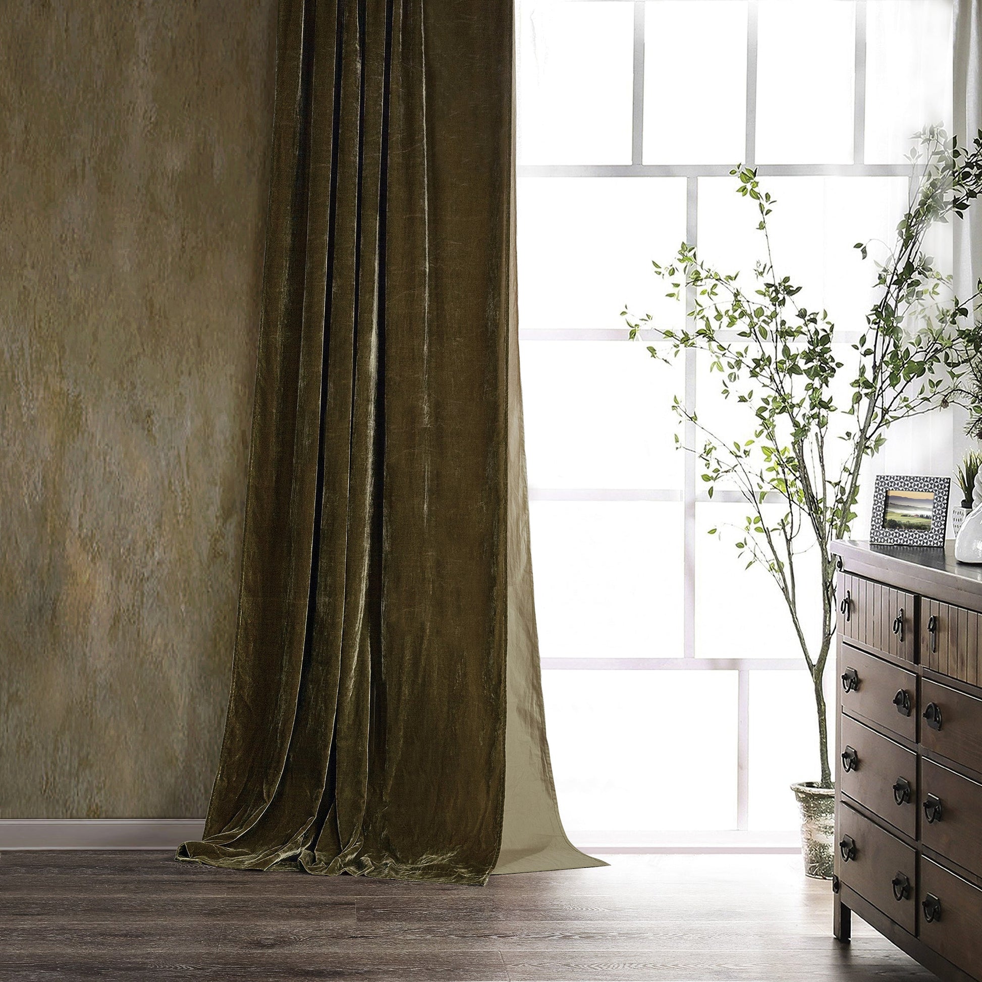 Brown velvet curtain in a room with a wooden dresser and window.