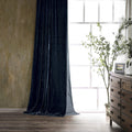 Dark blue curtain in a room with a wooden dresser and plant