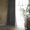 Dark gray curtain in a room with a wooden dresser and plant