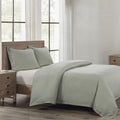 Bedroom with a bed featuring green bedding and wooden headboard and nightstands.