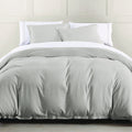 Gray comforter set on a bed with white pillows against a neutral wall.