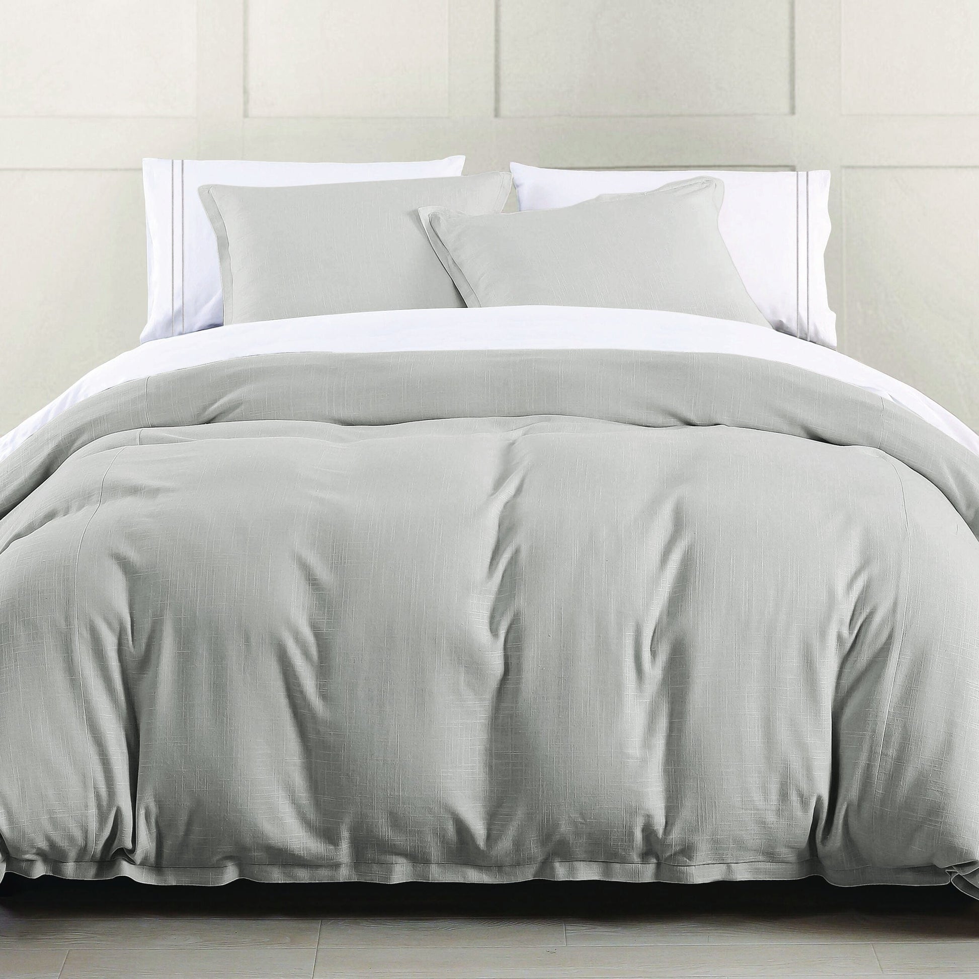 Gray comforter set on a bed with white pillows against a neutral wall.