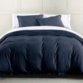 Navy blue comforter set on a bed with white pillows against a neutral wall.