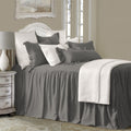 Bedroom with gray bedding and white pillows, featuring a lamp and framed picture on a wall.