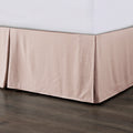 Beige bed skirt on a bed with a wooden floor.