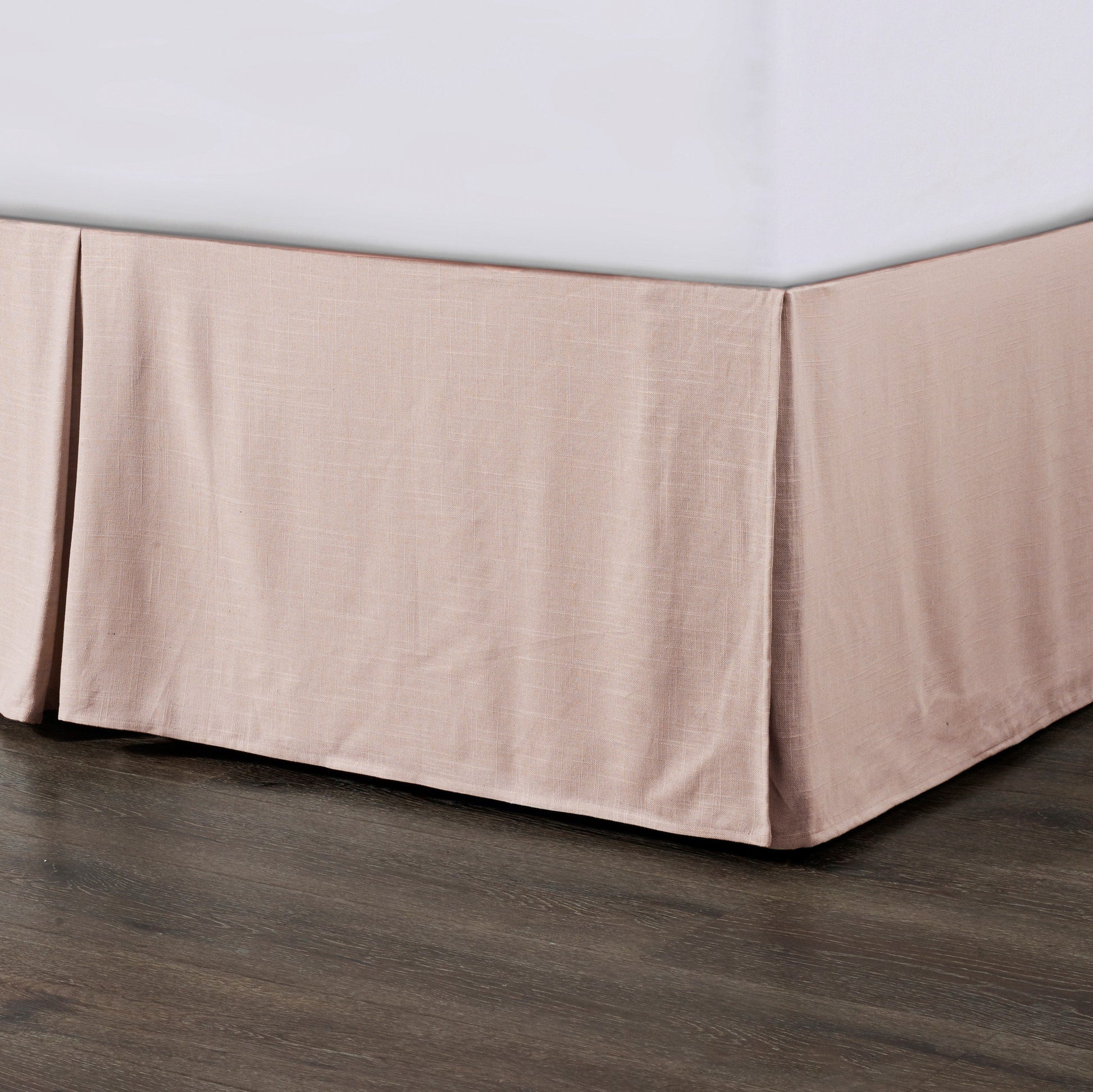 Beige bed skirt on a bed with a wooden floor.