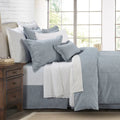 Bedroom with a neatly made bed featuring gray and white bedding, wooden nightstand, and large window.