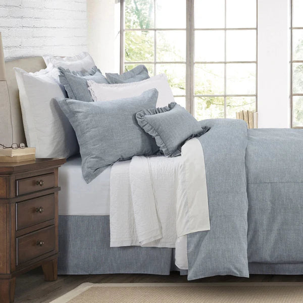 Bedroom with a neatly made bed featuring gray and white bedding, wooden nightstand, and large window.