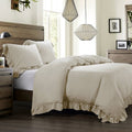 Neatly made bed with beige comforter and pillows in a bedroom setting.