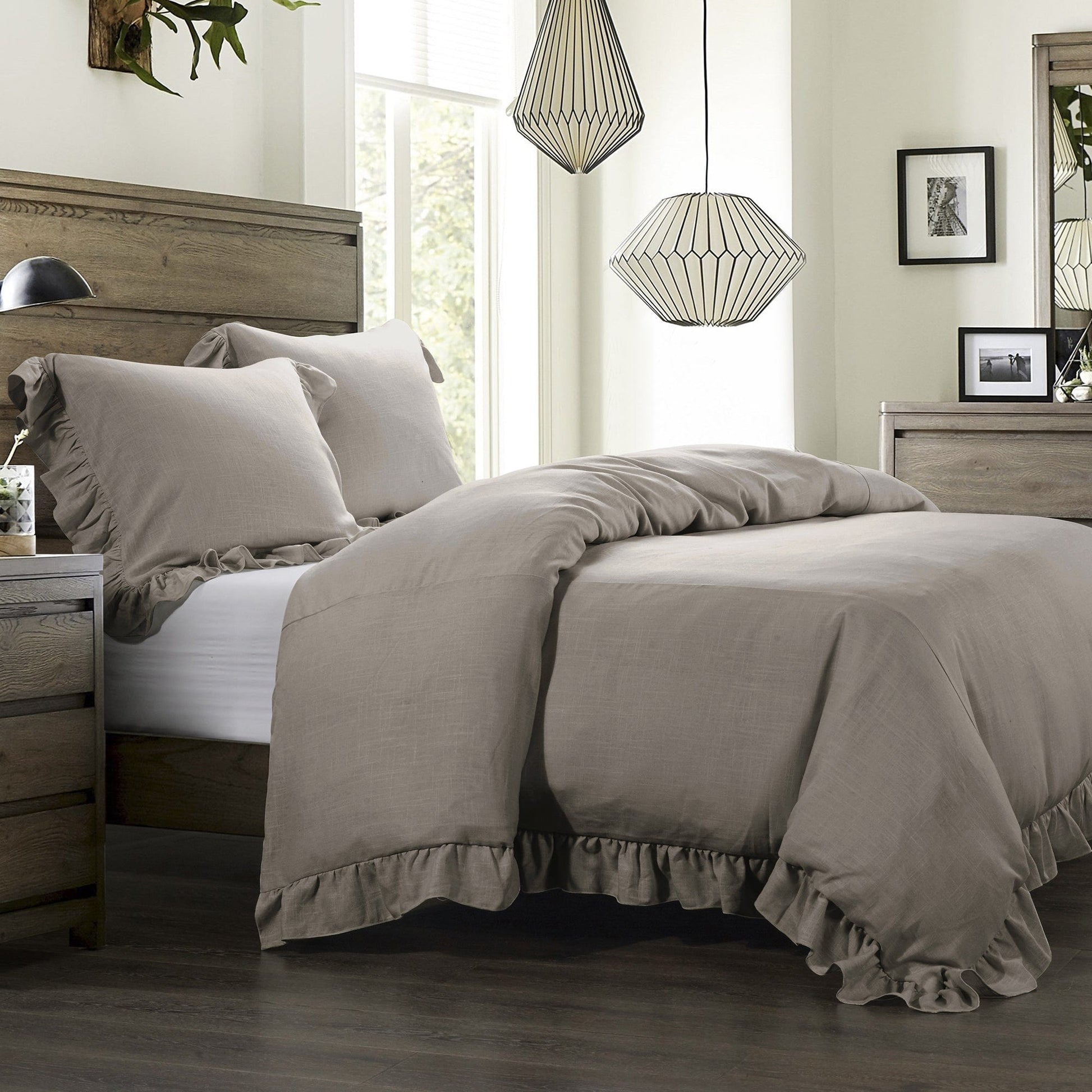 Neatly made bed with beige comforter and pillows in a bedroom setting.