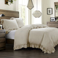 Neatly made bed with beige comforter and pillows in a well-lit bedroom.