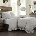 Neatly made bed with gray bedding in a well-lit bedroom.