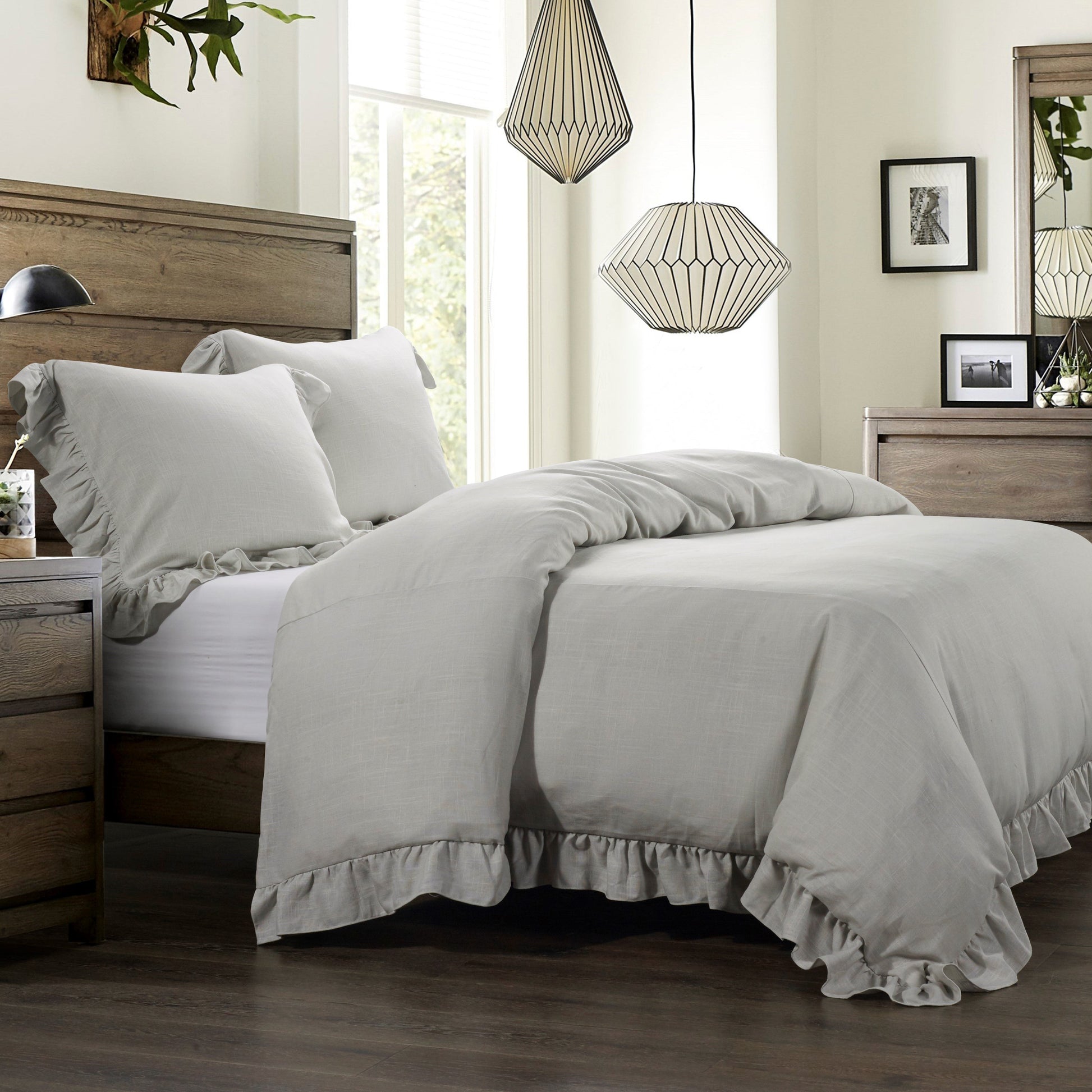 Neatly made bed with gray bedding in a well-lit bedroom.