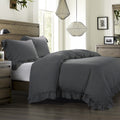 Gray bedding set on a bed in a bedroom with wooden furniture and decorative elements.