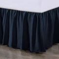 Dark blue bed skirt on a bed with a wooden floor.