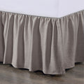 Brown bed skirt on a bed with a white mattress.