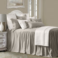 Neatly made bed with beige bedding and pillows in a bedroom setting.