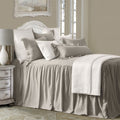 Neatly made bed with gray bedding and pillows in a bedroom setting.