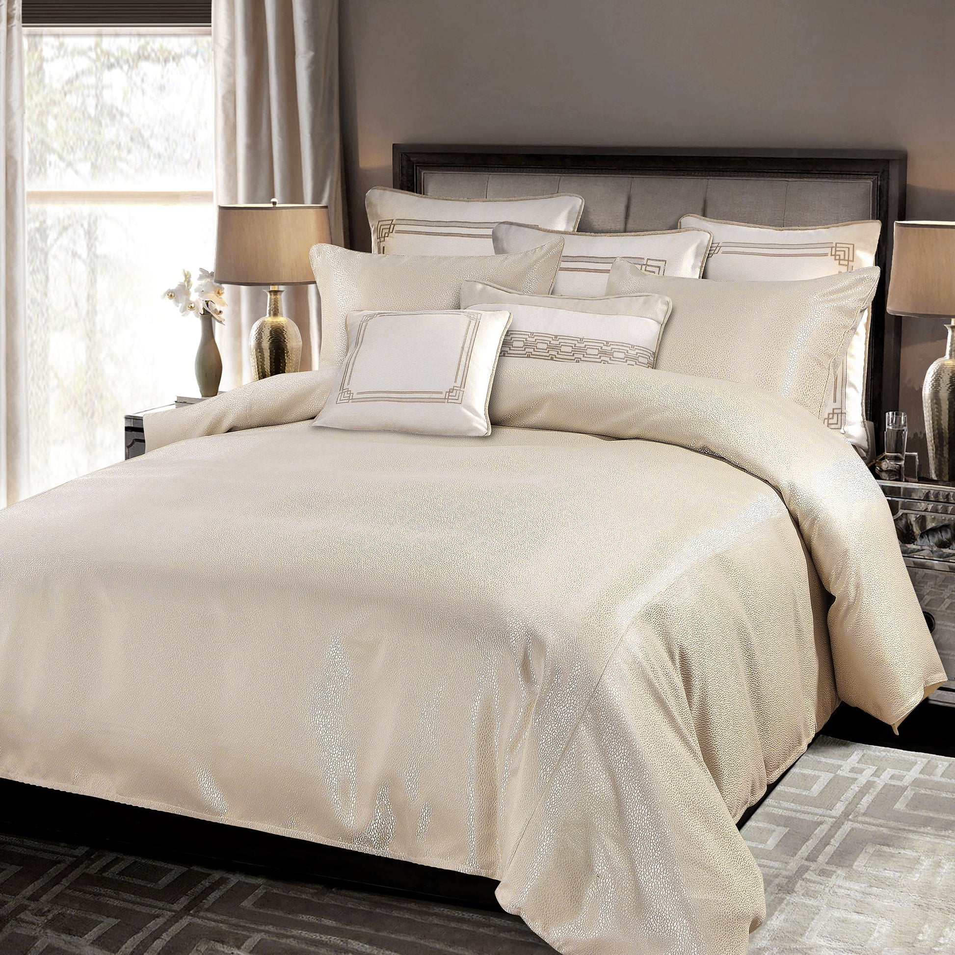 Beige bedding set on a bed in a bedroom with lamps and curtains.