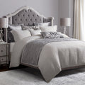 Gray upholstered bed with decorative pillows in a bedroom setting.