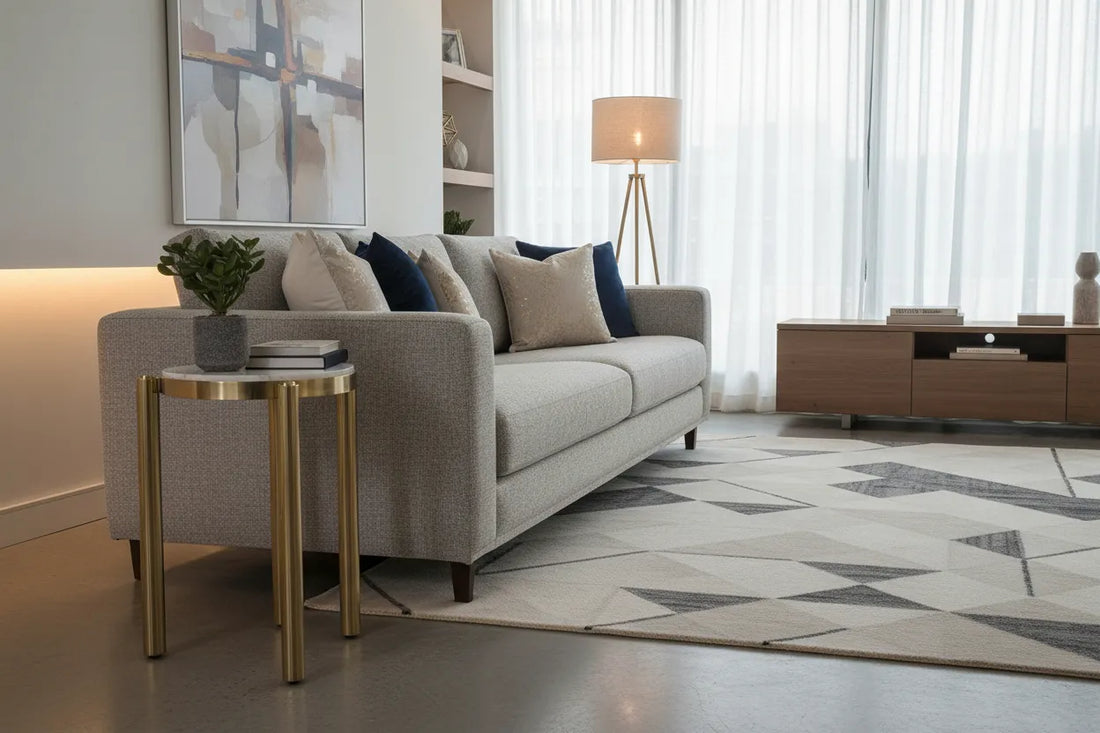 Modern living room with a gray sofa, noan white and gold side table, and decorative elements.