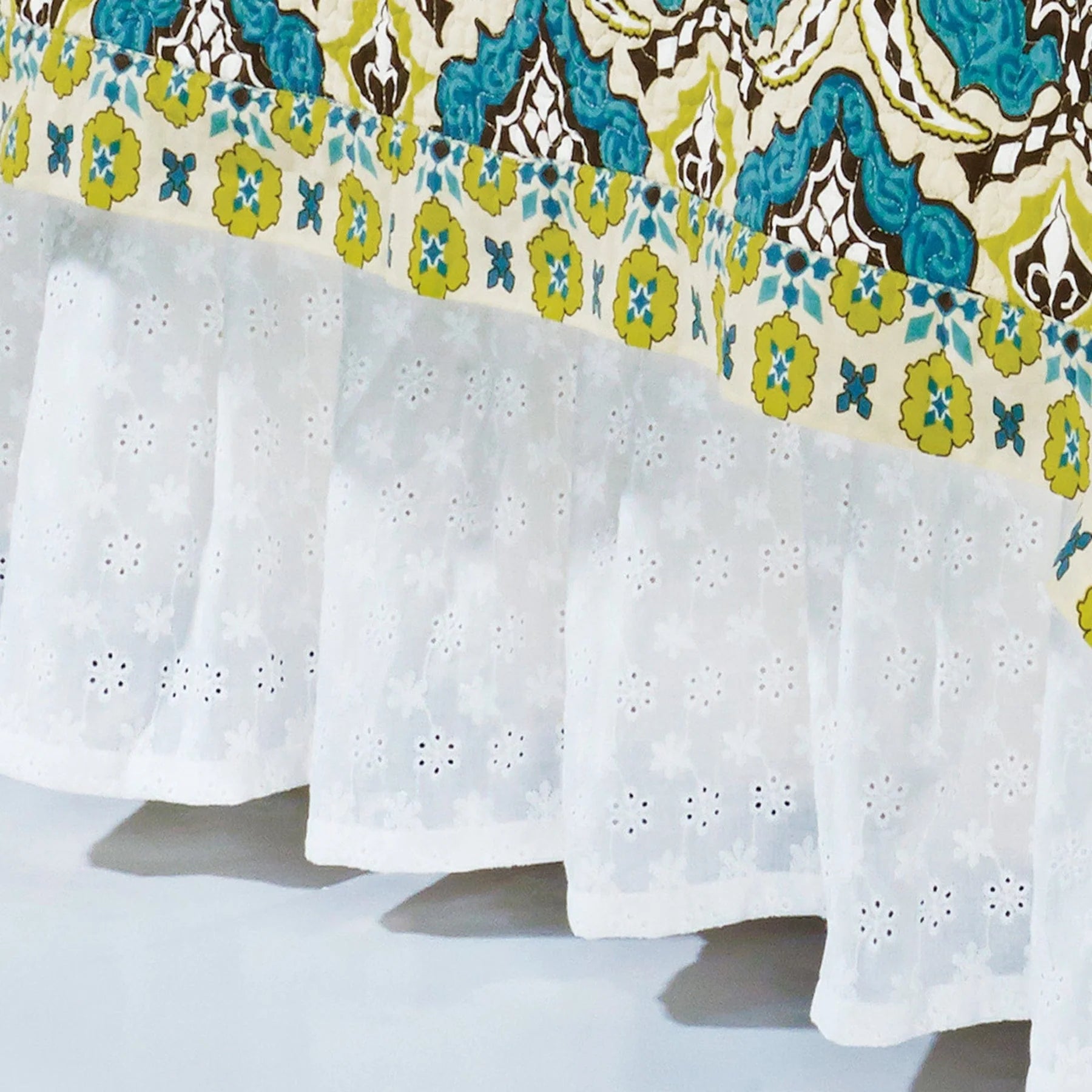 Tablecloth with colorful floral pattern on top and white eyelet design on the bottom