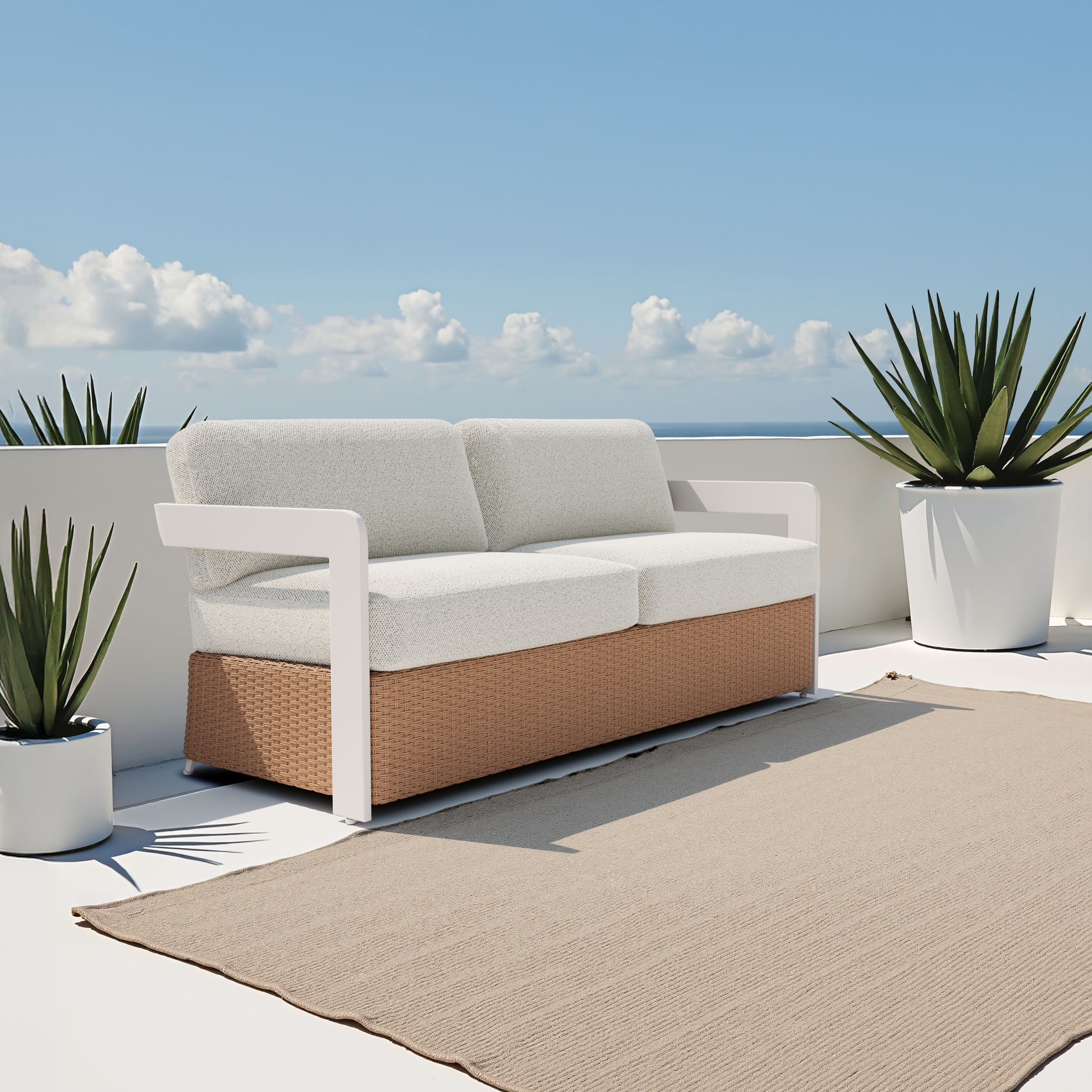 Outdoor sofa with white cushions and a brown wicker base on a patio with plants and blue sky.